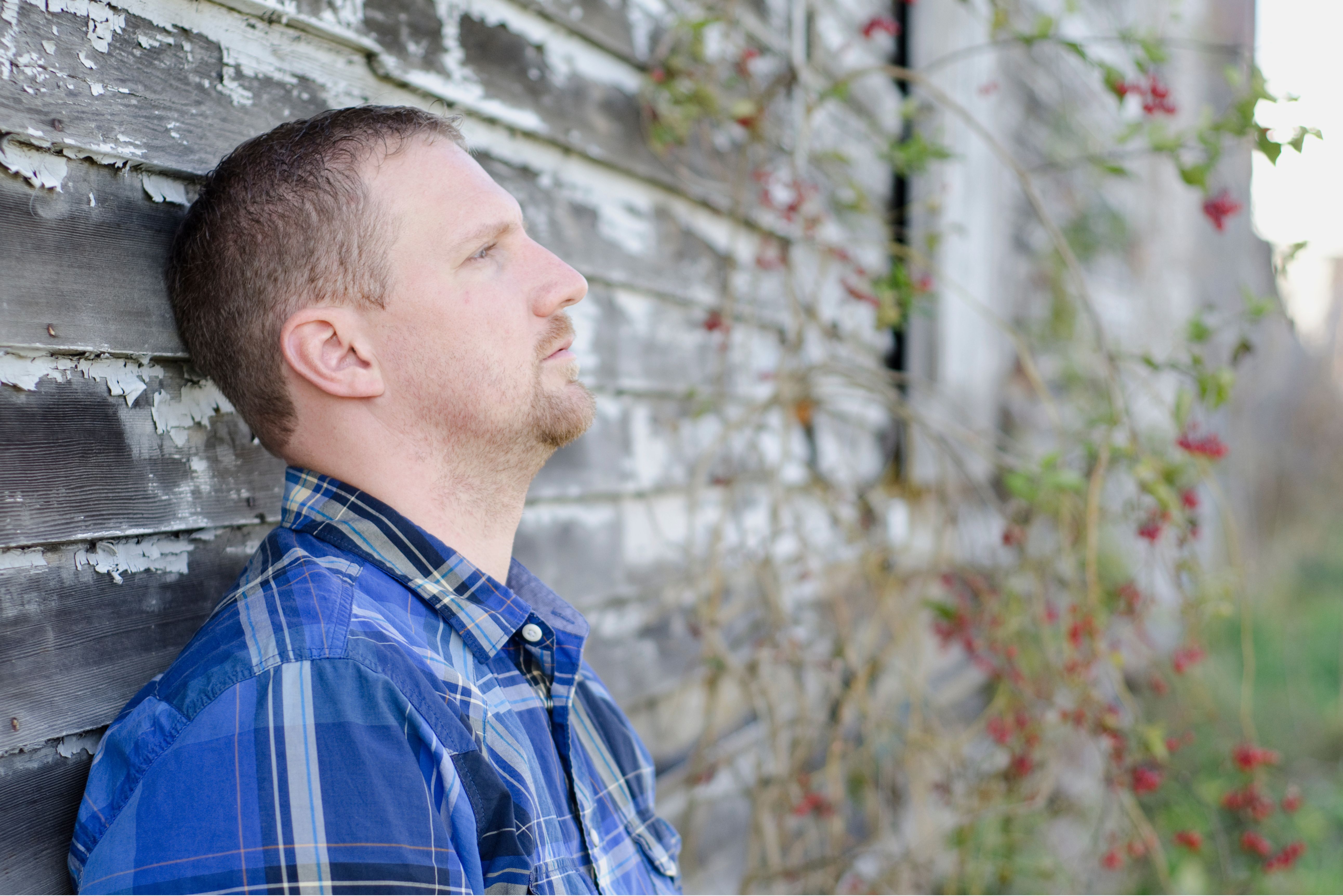 A man pondering against a wall outdoors